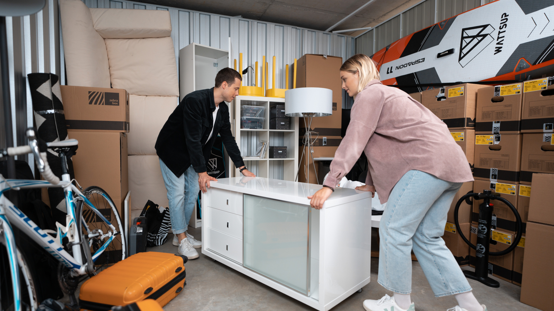 A young couple rolls a sideboard into the Zebrabox storage unit.