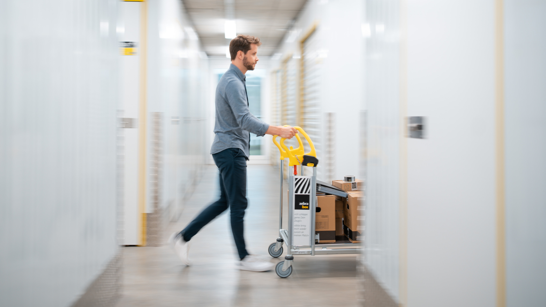 A man is pushing a trolley with moving boxes through the Zebrabox warehouse.